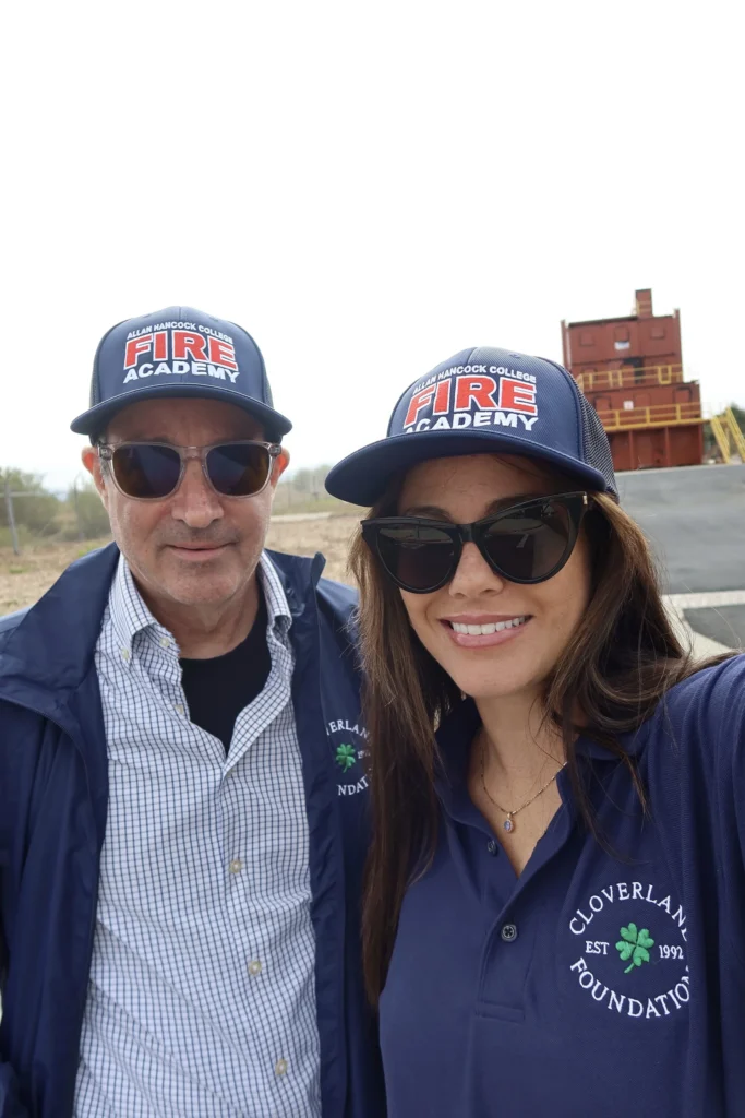 Two Cloverlane Foundation supporters in Fire Academy caps near the training tower